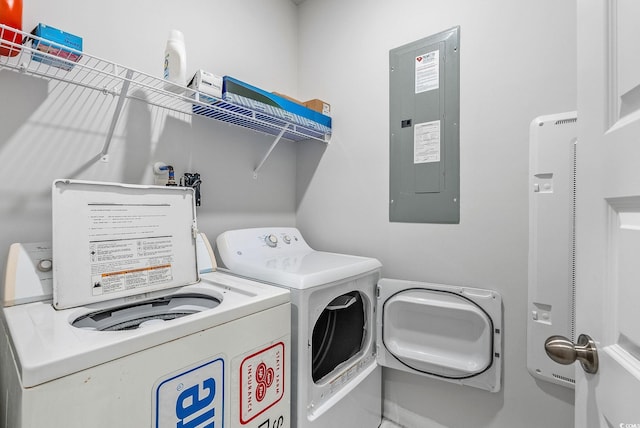 laundry room with electric panel and washing machine and clothes dryer