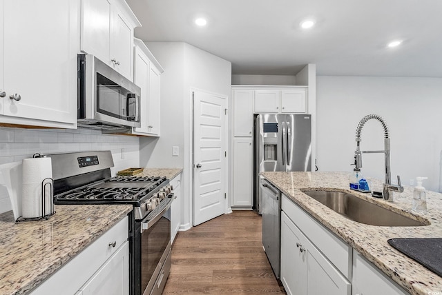 kitchen with appliances with stainless steel finishes, white cabinetry, sink, and dark hardwood / wood-style flooring