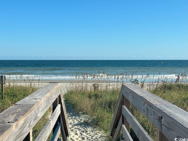 view of property's community featuring a water view and a beach view