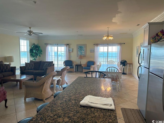 dining area with ceiling fan with notable chandelier, plenty of natural light, light tile patterned floors, and crown molding