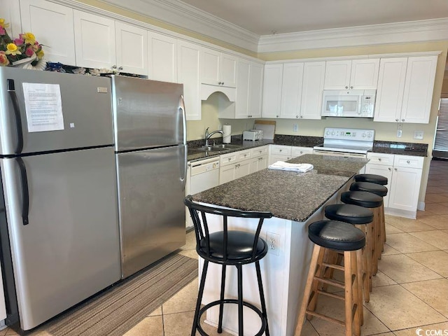 kitchen featuring white appliances, a breakfast bar, sink, ornamental molding, and white cabinetry