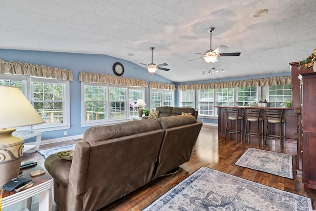 living room featuring a wealth of natural light, lofted ceiling, dark hardwood / wood-style floors, and ceiling fan