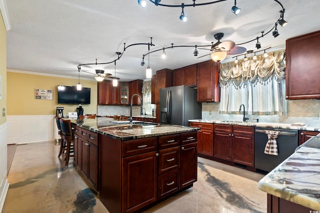 kitchen with a center island with sink, sink, tasteful backsplash, appliances with stainless steel finishes, and dark stone countertops