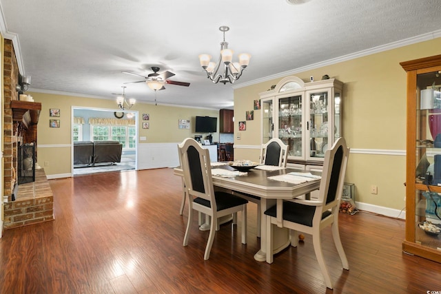 dining space featuring a fireplace, hardwood / wood-style flooring, ceiling fan with notable chandelier, and crown molding