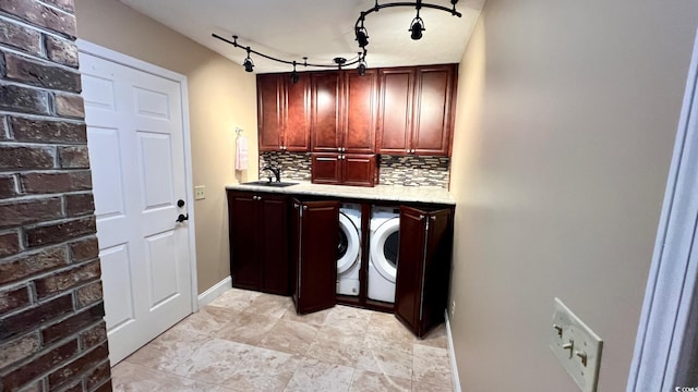 laundry area with track lighting, cabinets, sink, and separate washer and dryer