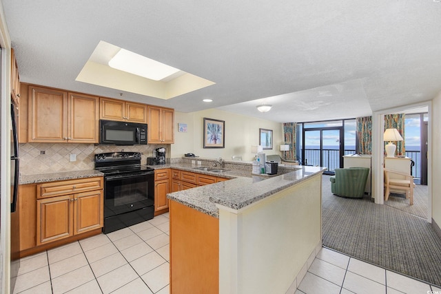 2301 Ocean Blvd S Unit 1218, Myrtle Beach, SC 29577 - kitchen with black appliances, a peninsula, light tile patterned floors, a sink, and backsplash