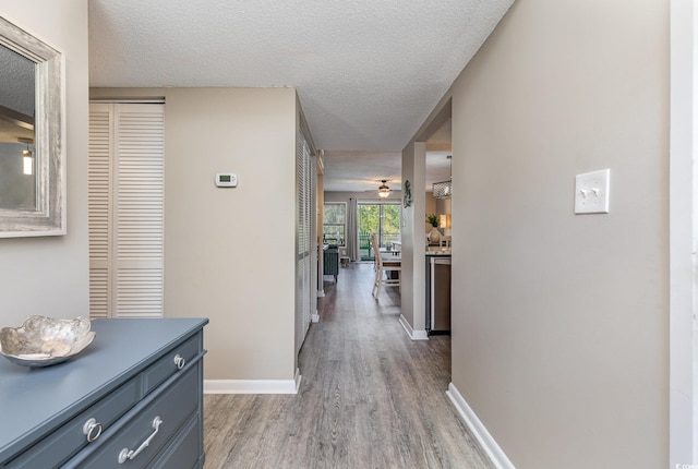 corridor with light hardwood / wood-style floors and a textured ceiling