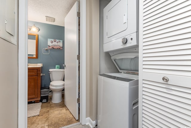 clothes washing area with stacked washer / dryer and a textured ceiling