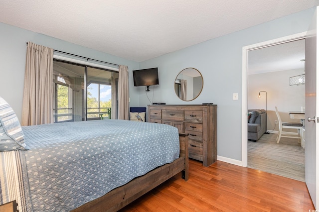 bedroom featuring access to exterior, a textured ceiling, and hardwood / wood-style floors