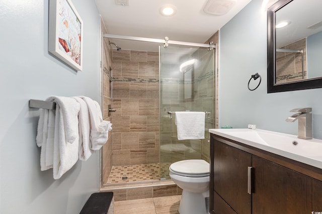 bathroom with tile patterned flooring, a shower with door, vanity, and toilet