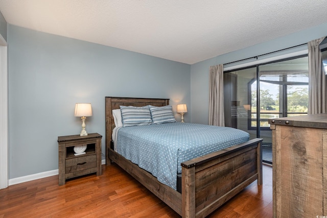 bedroom featuring a textured ceiling, access to exterior, and dark hardwood / wood-style flooring