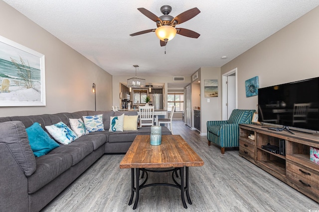 living room featuring ceiling fan, hardwood / wood-style floors, and a textured ceiling