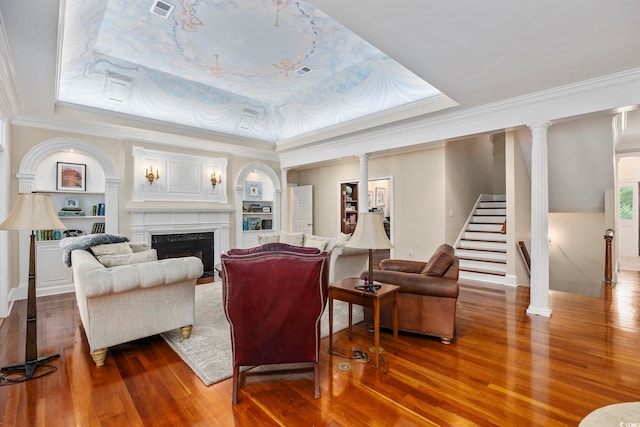 living room featuring ornamental molding, wood finished floors, and a raised ceiling