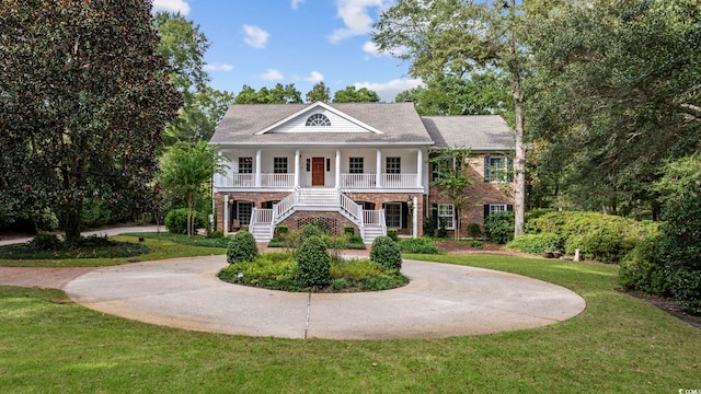 neoclassical / greek revival house featuring stairway, a porch, a front lawn, and curved driveway