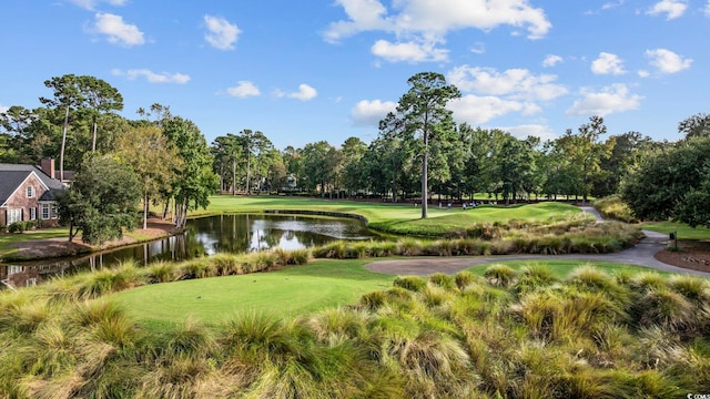 view of property's community with view of golf course, a lawn, and a water view