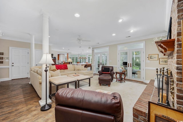 living area with french doors, ornamental molding, decorative columns, wood finished floors, and a ceiling fan