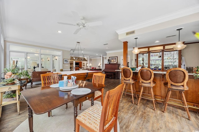 dining area with visible vents, a wealth of natural light, ceiling fan, light wood-type flooring, and crown molding