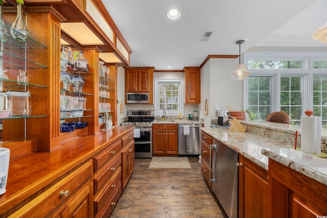 kitchen with dark wood finished floors, light stone counters, stainless steel appliances, ornamental molding, and a sink
