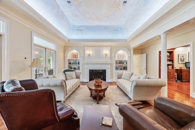 living area featuring visible vents, a raised ceiling, wood finished floors, and crown molding