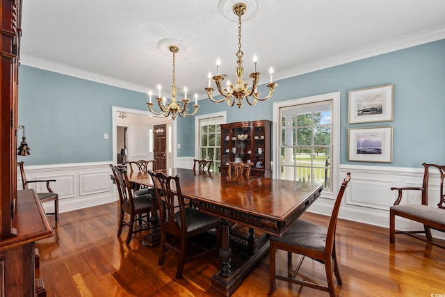 dining area with crown molding, a wainscoted wall, a notable chandelier, and dark wood finished floors