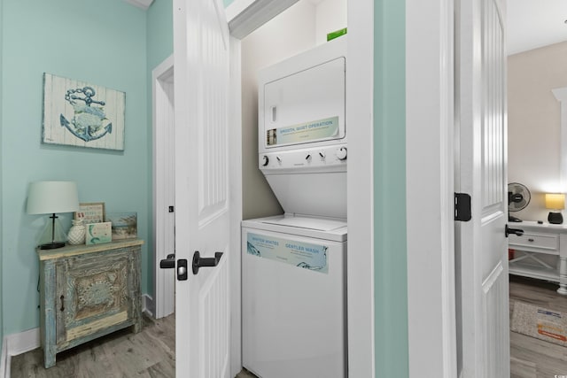 clothes washing area with light hardwood / wood-style flooring and stacked washer and clothes dryer