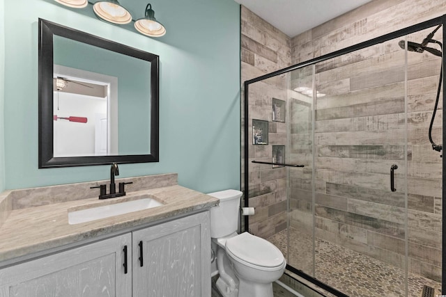 bathroom featuring vanity, toilet, and a shower with shower door