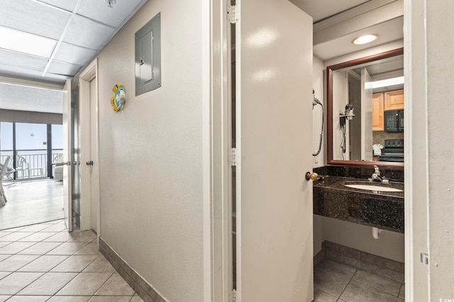 corridor featuring electric panel, sink, and light tile patterned floors