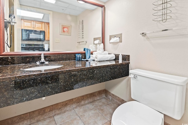 half bathroom featuring a sink, toilet, and tile patterned floors