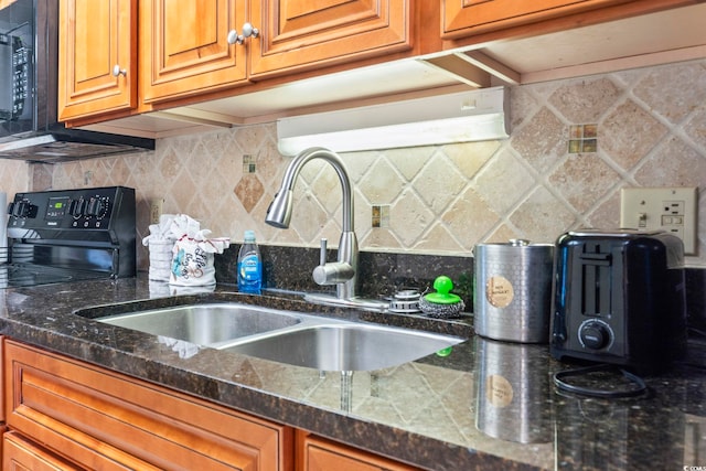 kitchen with dark stone counters, black appliances, decorative backsplash, and sink