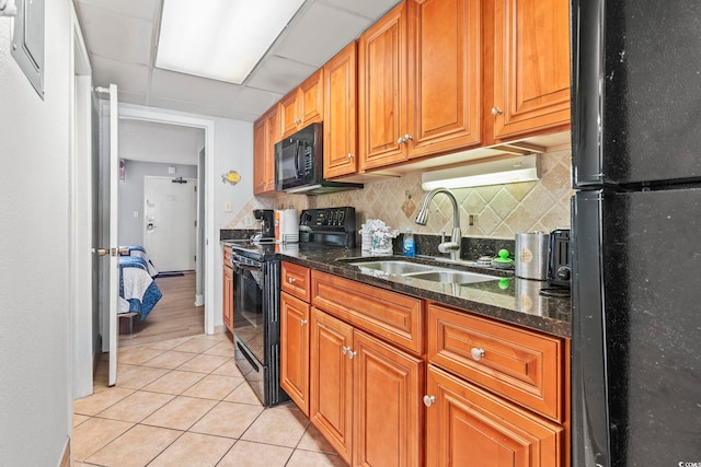 kitchen with light tile patterned flooring, sink, black appliances, dark stone counters, and decorative backsplash