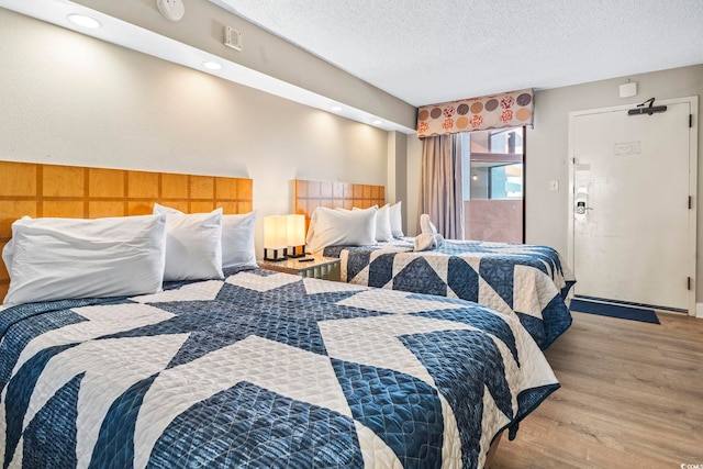 bedroom featuring a textured ceiling and light hardwood / wood-style flooring