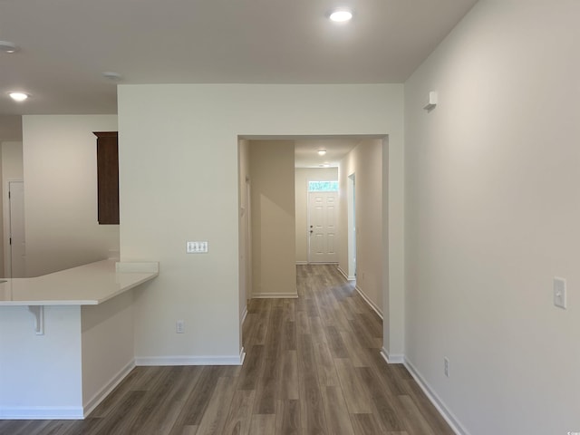 hall featuring baseboards, dark wood-style flooring, and recessed lighting