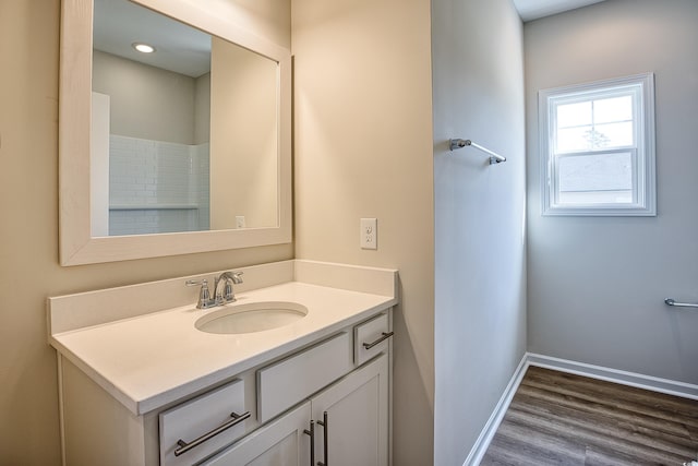 full bath with wood finished floors, vanity, and baseboards