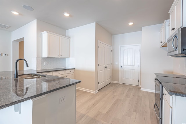 kitchen with white cabinets, a peninsula, stainless steel appliances, and a sink