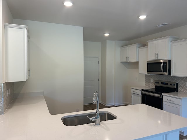 kitchen with range with electric stovetop, a sink, white cabinets, light countertops, and stainless steel microwave