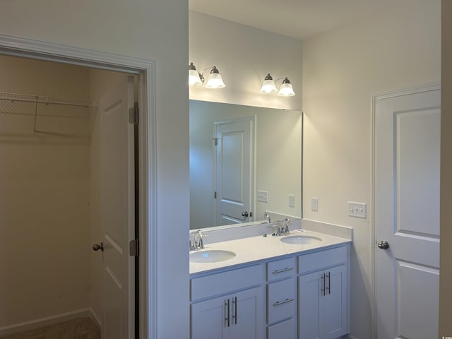 bathroom with double vanity, a spacious closet, and a sink