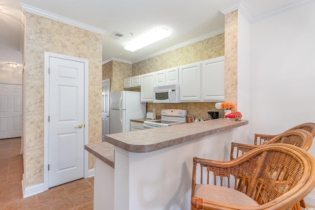 kitchen featuring white appliances, kitchen peninsula, crown molding, white cabinetry, and a kitchen breakfast bar