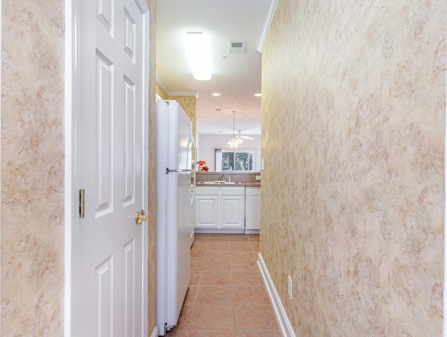 corridor featuring ornamental molding, sink, light tile patterned floors, and a textured ceiling