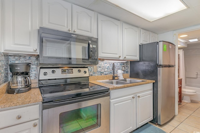 kitchen with light tile patterned flooring, white cabinets, appliances with stainless steel finishes, and sink