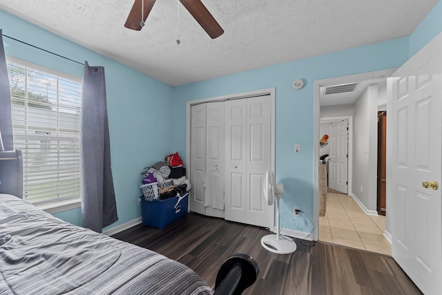 bedroom featuring multiple windows, hardwood / wood-style floors, a textured ceiling, and ceiling fan