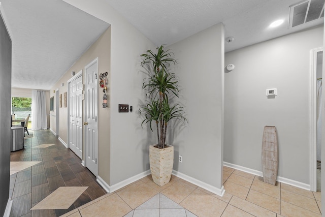 corridor featuring a textured ceiling and light tile patterned floors