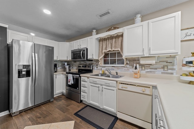 kitchen featuring white cabinetry, appliances with stainless steel finishes, dark hardwood / wood-style floors, decorative backsplash, and sink