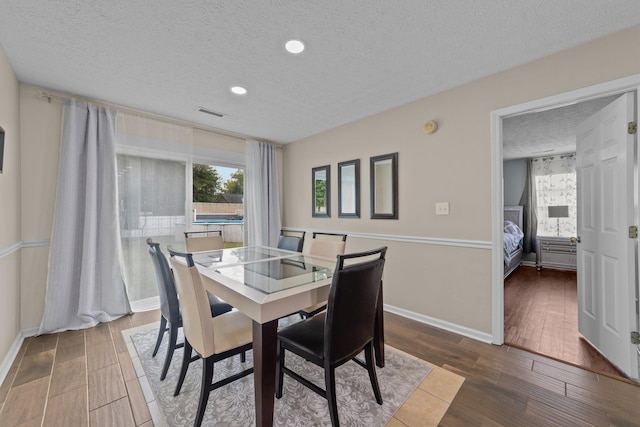 dining room with wood-type flooring and a textured ceiling