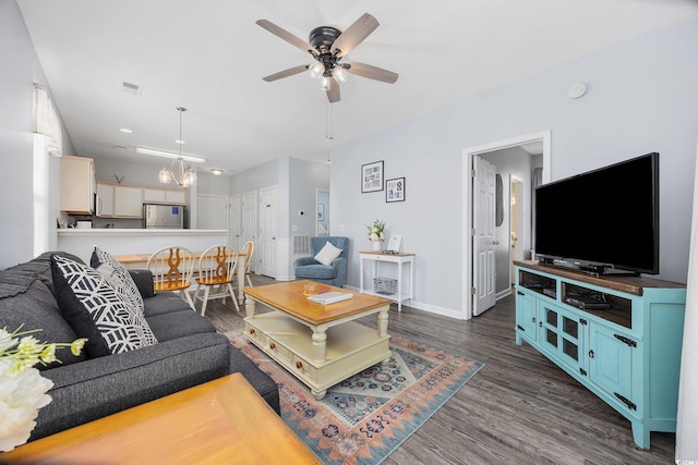 living room with ceiling fan with notable chandelier and dark hardwood / wood-style flooring