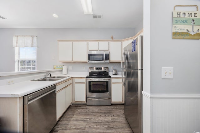 kitchen featuring sink, appliances with stainless steel finishes, dark hardwood / wood-style floors, kitchen peninsula, and white cabinets