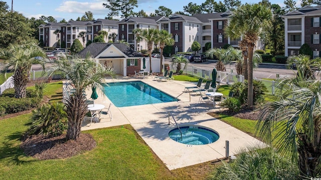 view of swimming pool featuring a community hot tub, a yard, a patio area, and an outbuilding