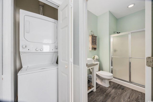 laundry room featuring dark hardwood / wood-style flooring and stacked washer and dryer