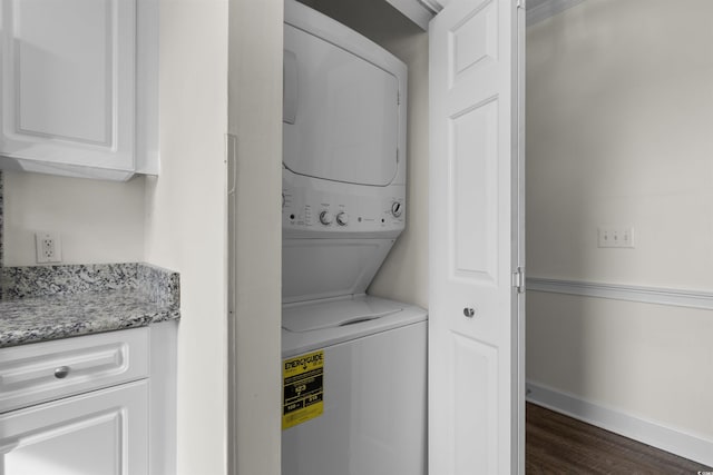 laundry room with dark hardwood / wood-style flooring and stacked washer / drying machine