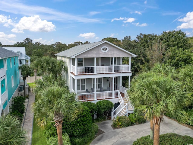 coastal inspired home with covered porch, stairway, and a balcony