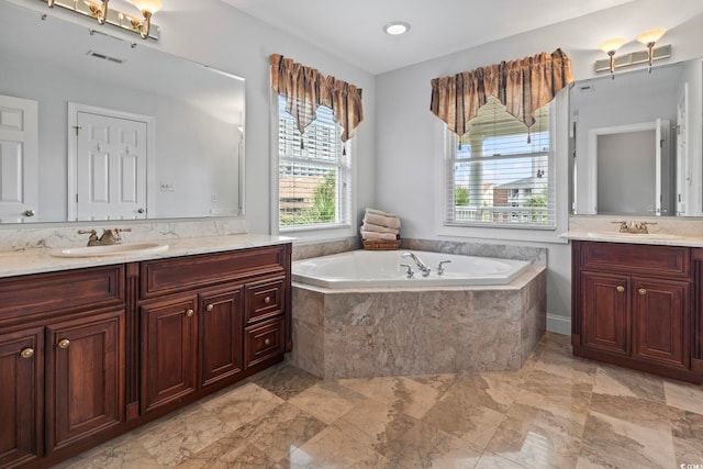 full bath featuring two vanities, a bath, visible vents, and a sink